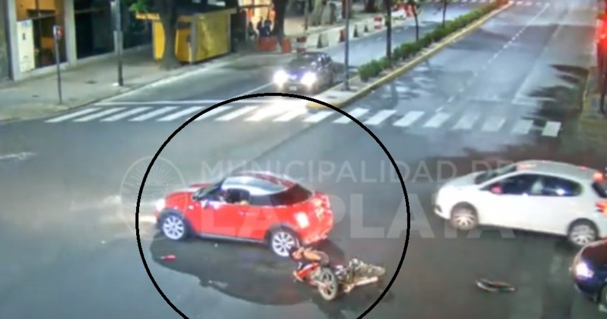Tras el golpe, el motociclista cae al asfalto y la conductora del vehículo se baja para asistirlo.